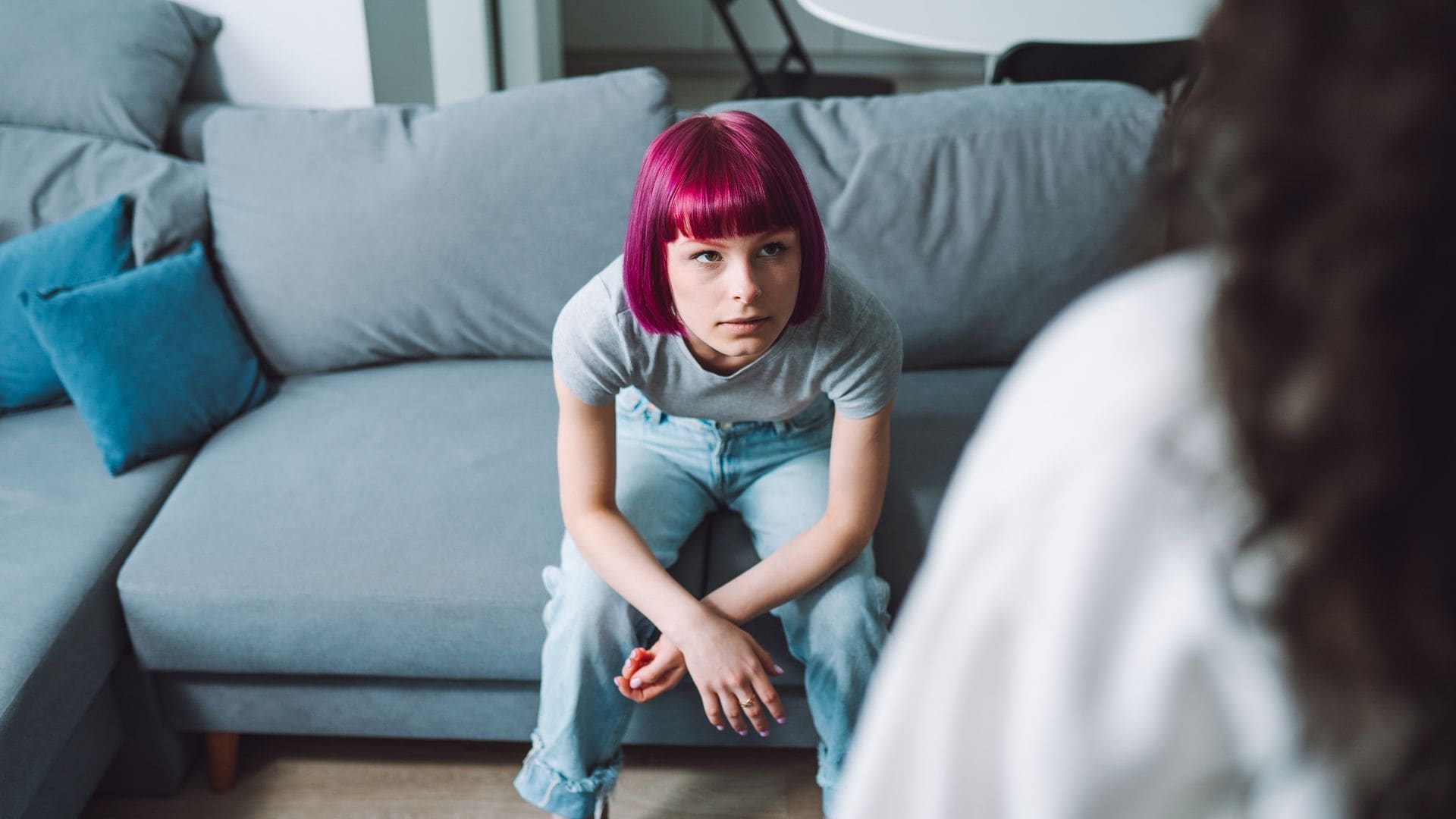 Adolescente con el pelo morado escucha a su madre, enfadada