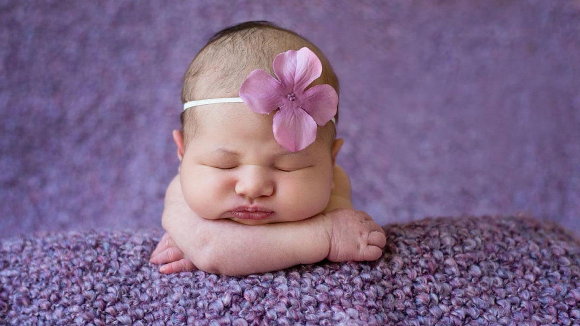 beb con una flor morada en la cabeza