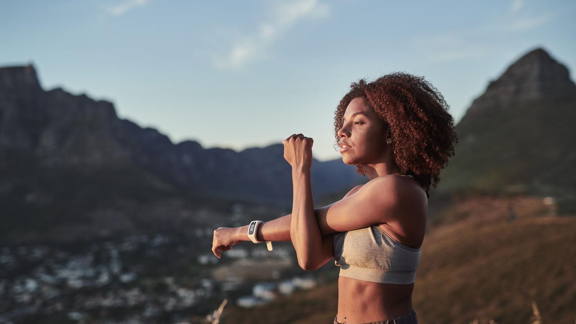 shot of a young woman stretching while out for a workout on a mountain road