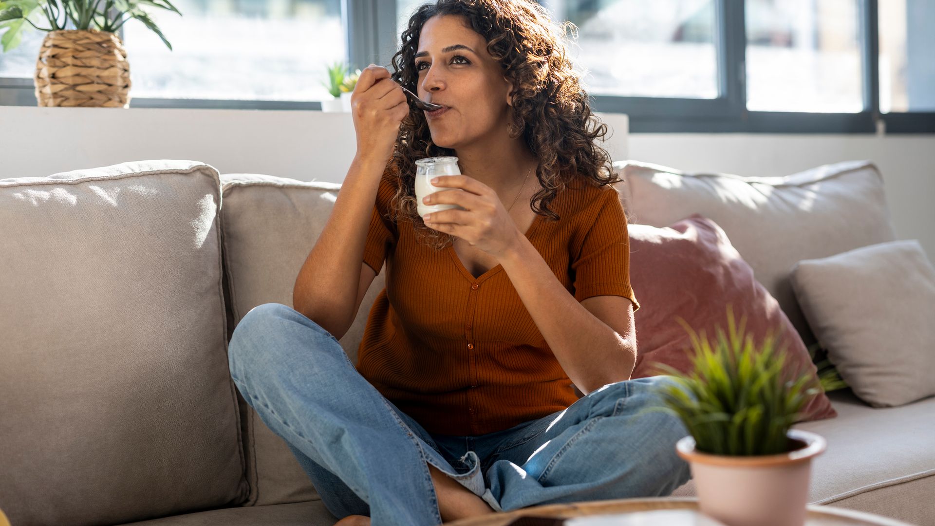 Mujer tomando un yogur en el sofá de su casa