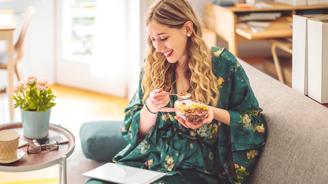 mujer desayunando en el sofá de casa