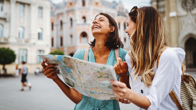 dos amigas sonrientes haciendo turismo en vacaciones, con un mapa en la mano
