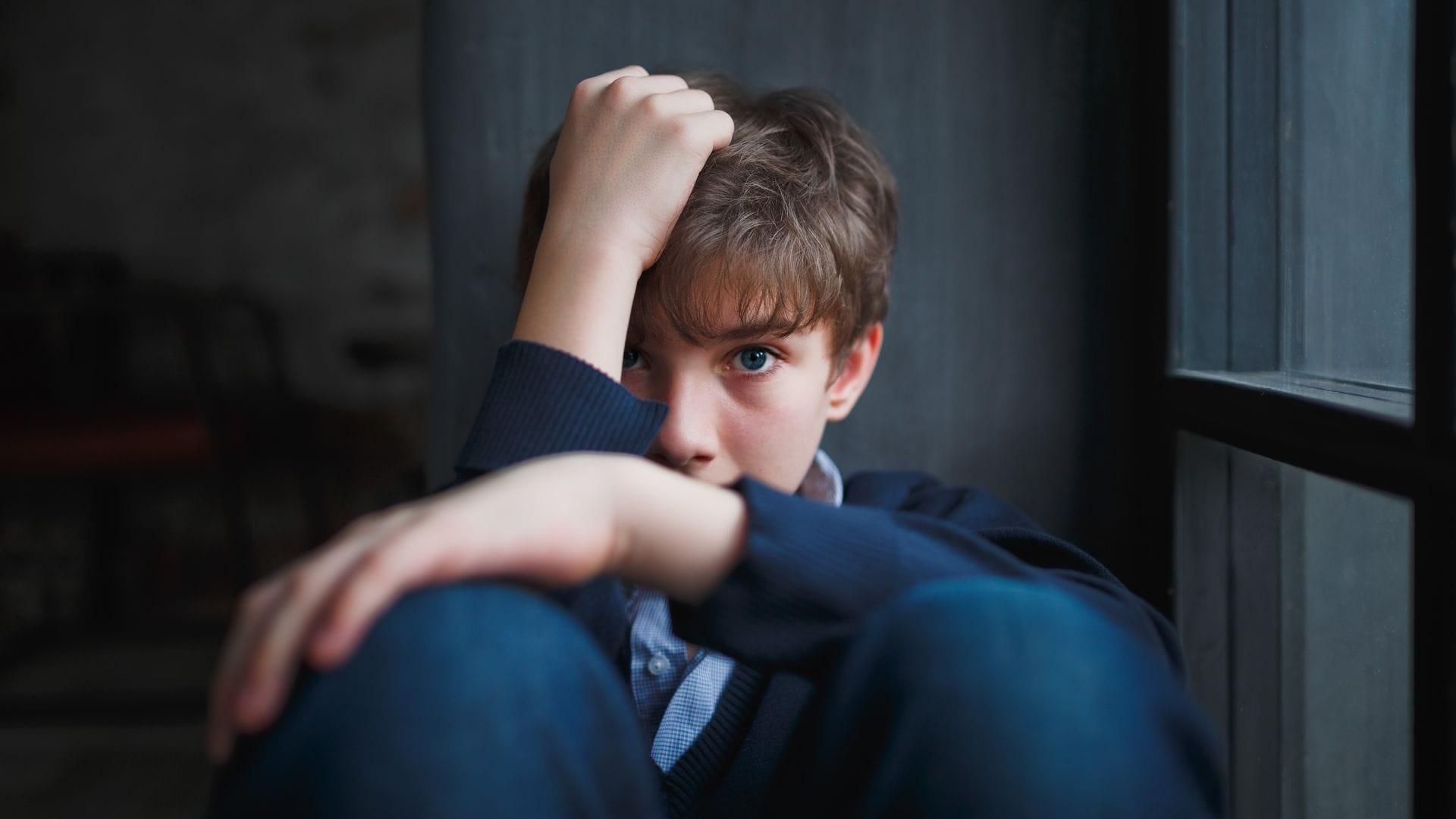 Adolescente serio tras la ventana