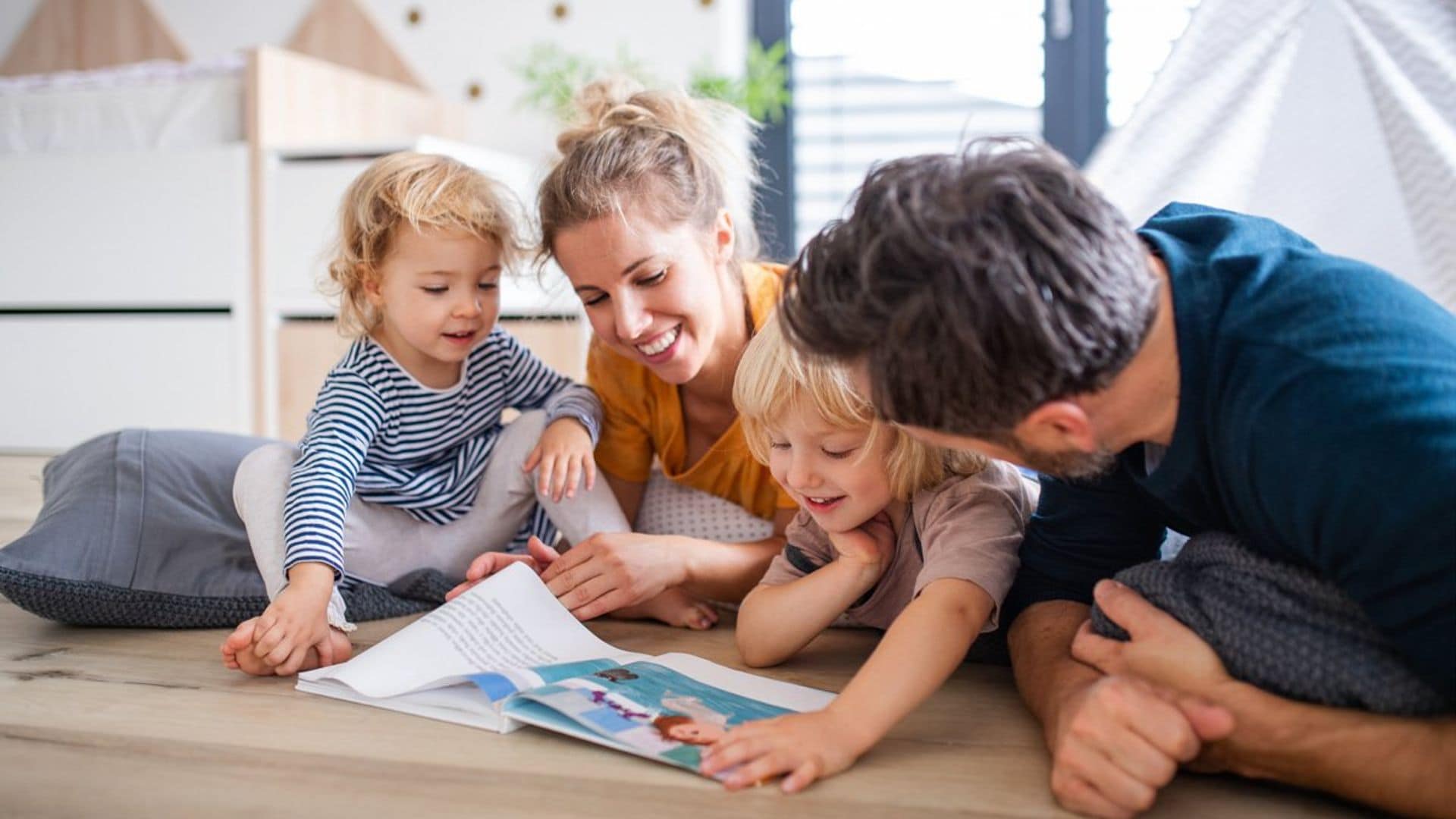 ni os jugando con sus padres en casa con un libro 