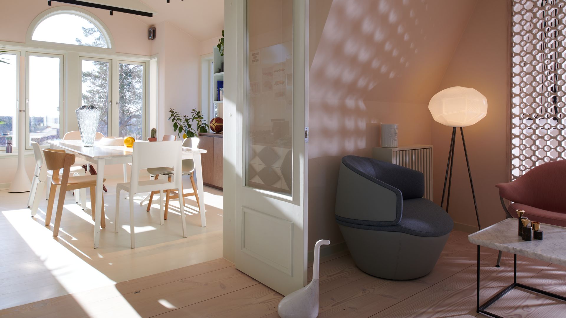 Cocina abierta al salón con mesa de comedor blanca, salida al jardín, puerta blanca con cuarterones de cristal