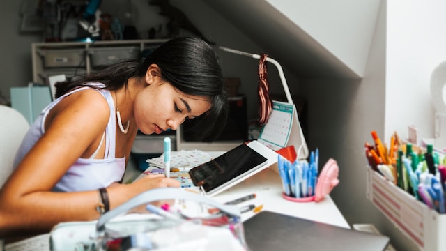 Niña adolescente haciendo deberes y estudiando tras volver del colegio