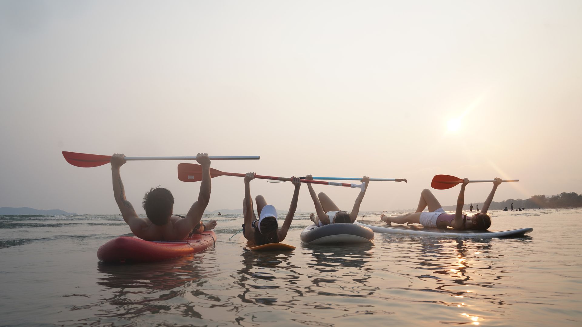 Grupo de amigos en tablas de 'paddle surf' en la playa en verano