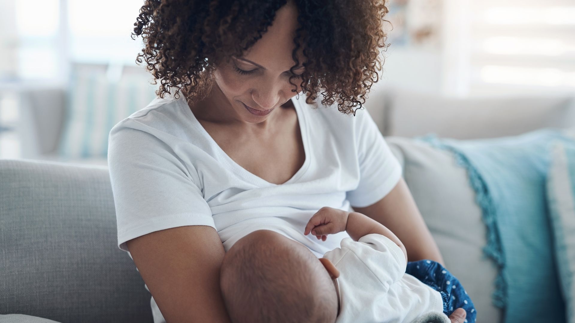 Madre amamantando a su bebé en el sofá