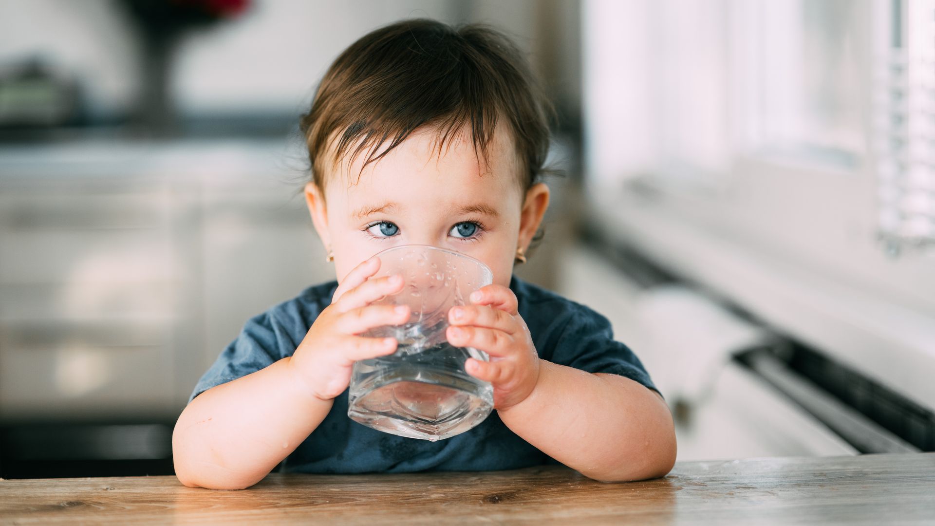 Niña pequeña bebe un vaso de agua