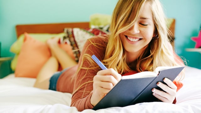 Chica escribiendo en su diario en la cama