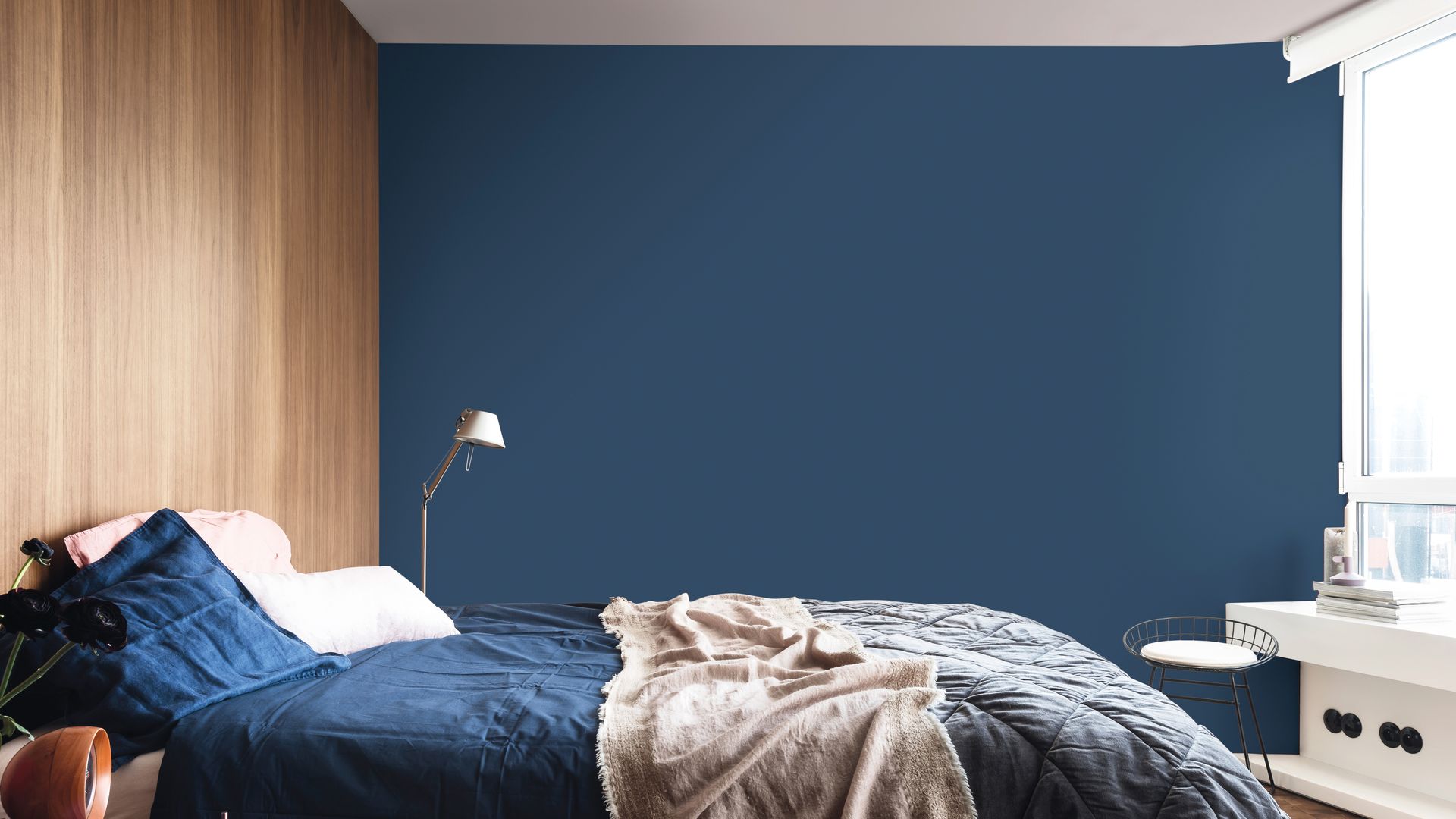 Dormitorio con pared azul oscura y pared del cabecero en madera 