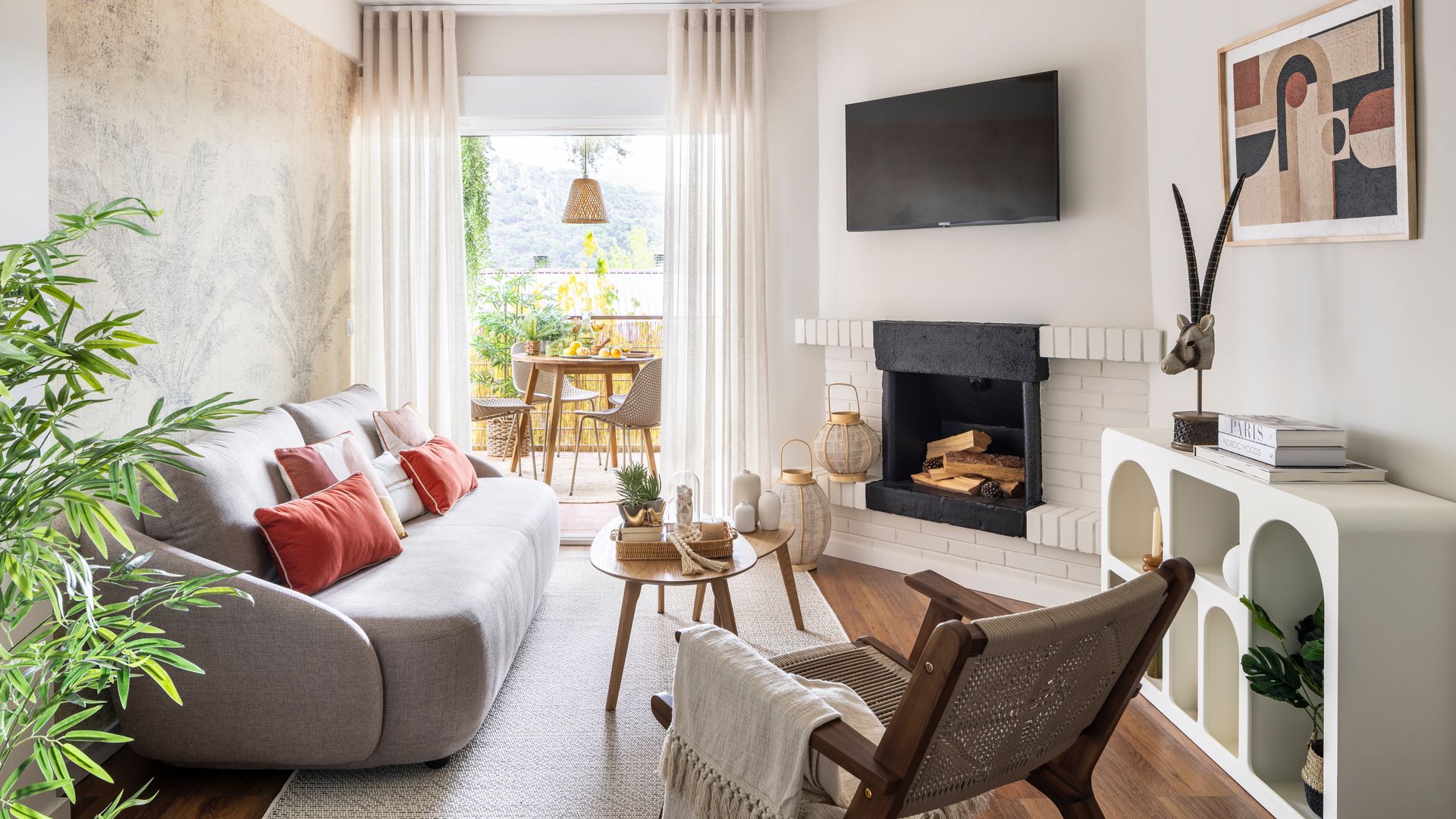 Salón con chimenea negra, pared pintado pared del sofá, ventilador de techo y sofá gris con cojines naranjas