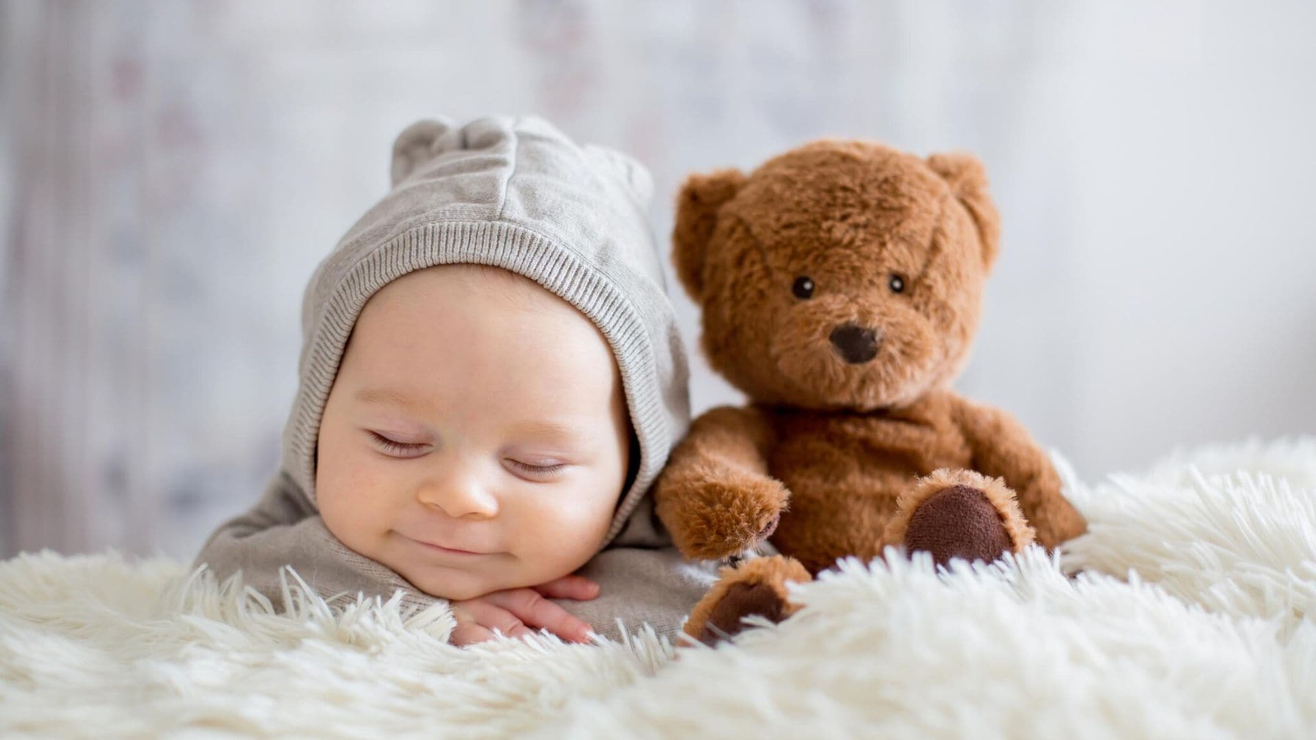 sweet baby boy in bear overall sleeping in bed with teddy bear