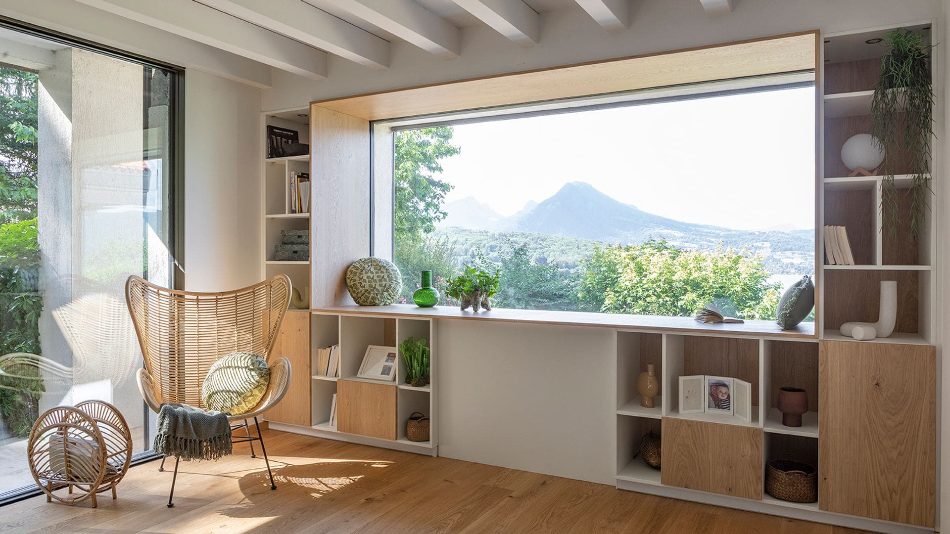 Mueble a medida alrededor de una ventana con vistas al campo, silla de fibras vegetales y revistero