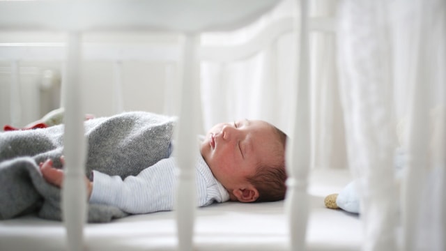 Un bebé recién nacido durmiendo en la cuna