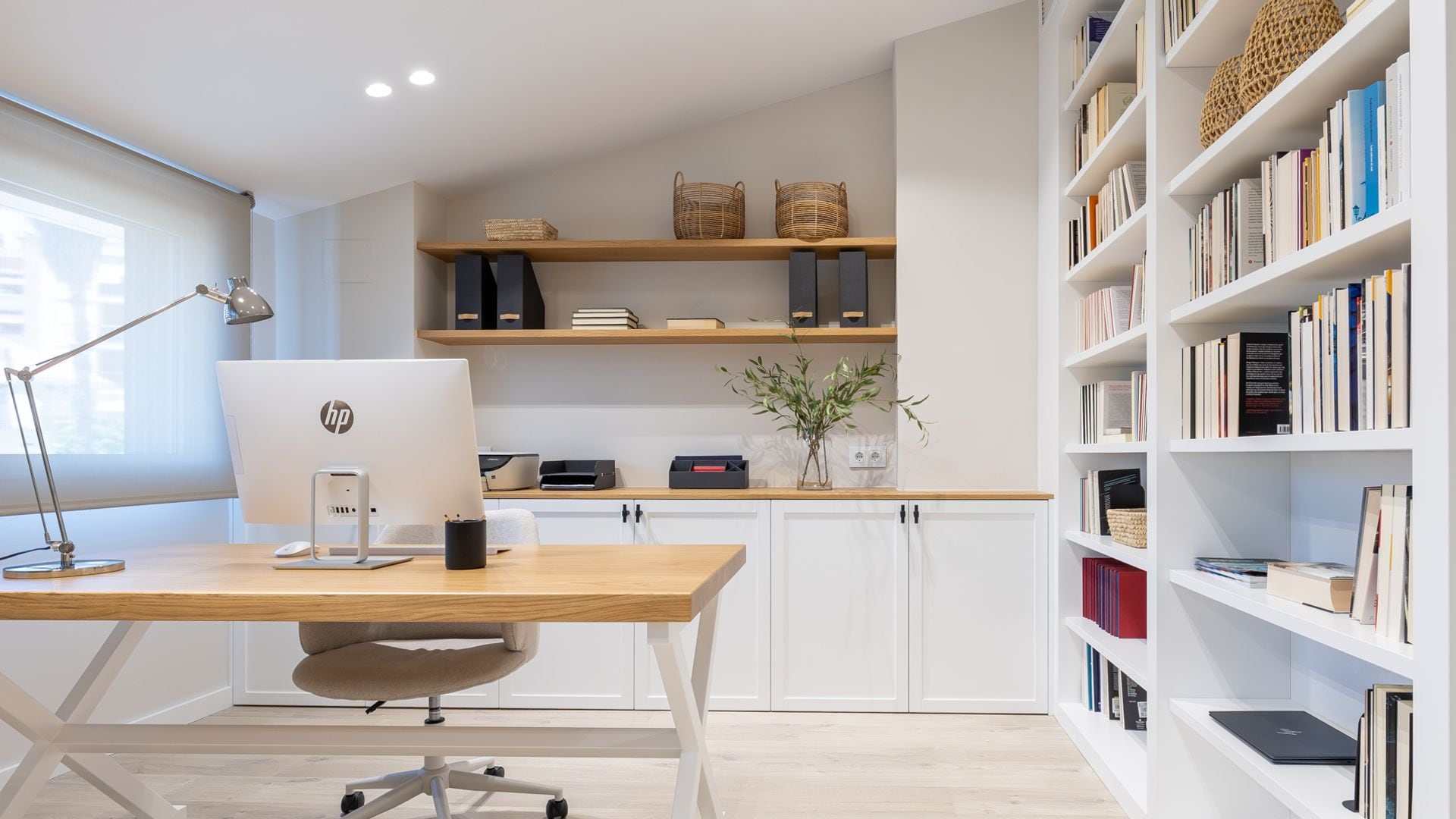 Despacho con mueble a medida con baldas y puertas, mesa con el sobre de madera, ordenador y silla con ruedas