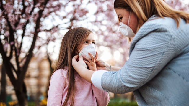 madre poniendo mascarilla ffp2 a una ni a en el parque 