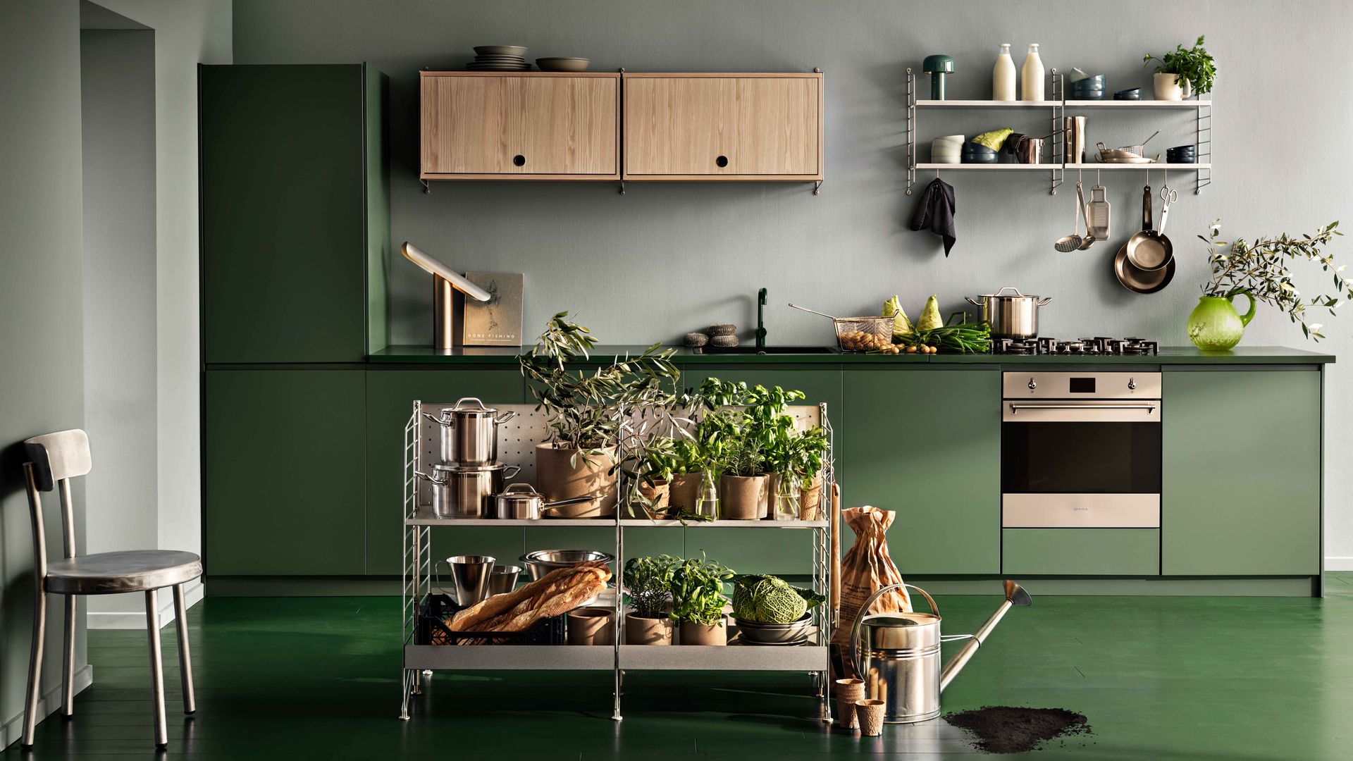 Cocina con muebles y suelo verde, estanterías metálicas en la pared y en el suelo