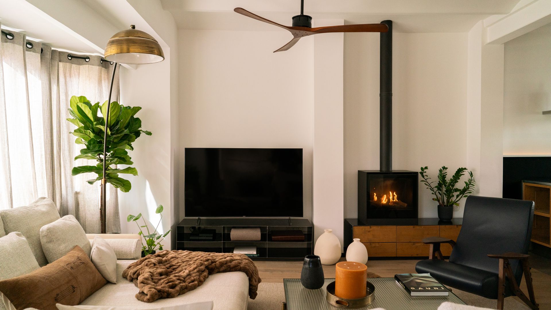 Salón con chimenea, ventilador de techo y mueble de televisión