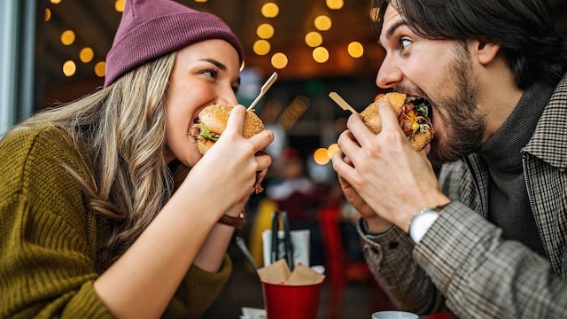 el peso un factor determinante para la infertilidad pareja comiendo una hamburguesa 