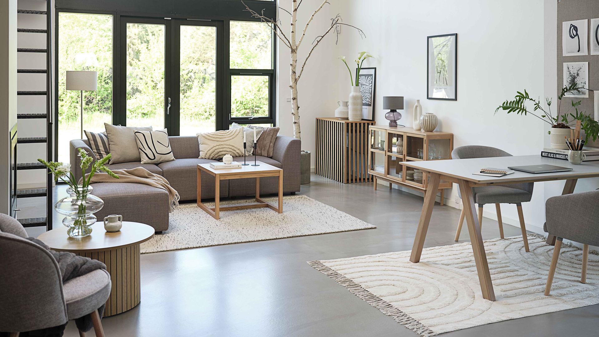 Salón comedor de estilo minimalista con sofás grises, alfombras blancas y mesas de madera