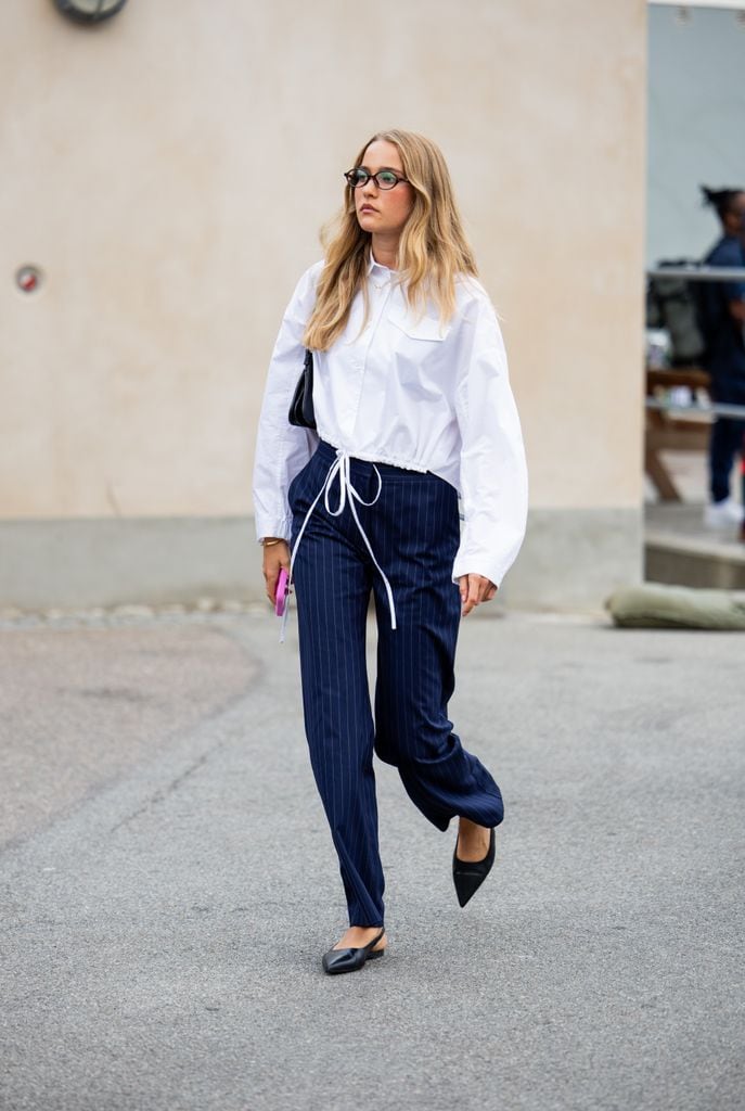 Un invitado lleva camisa blanca de botones, pantalones a rayas azul marino fuera de Baum & Pferdgarten durante el tercer día de la Semana de la Moda de Copenhague (CPHFW) SS25 el 07 de agosto 2024 en Copenhague, Dinamarca.