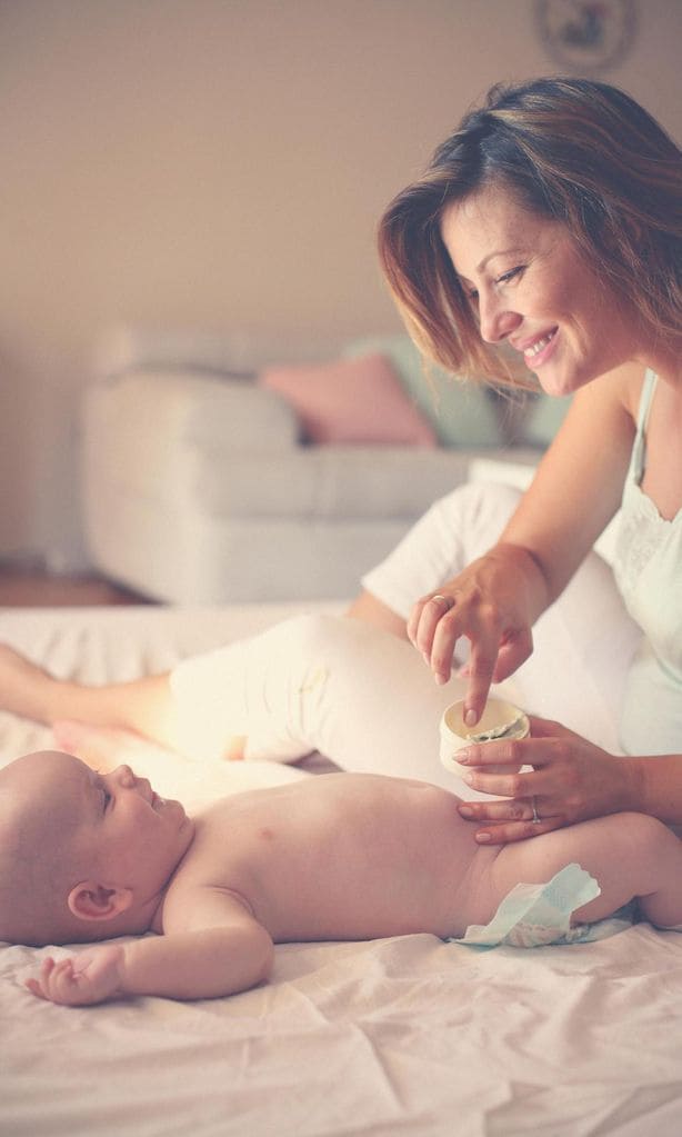 Mamá poniendo crema a bebé