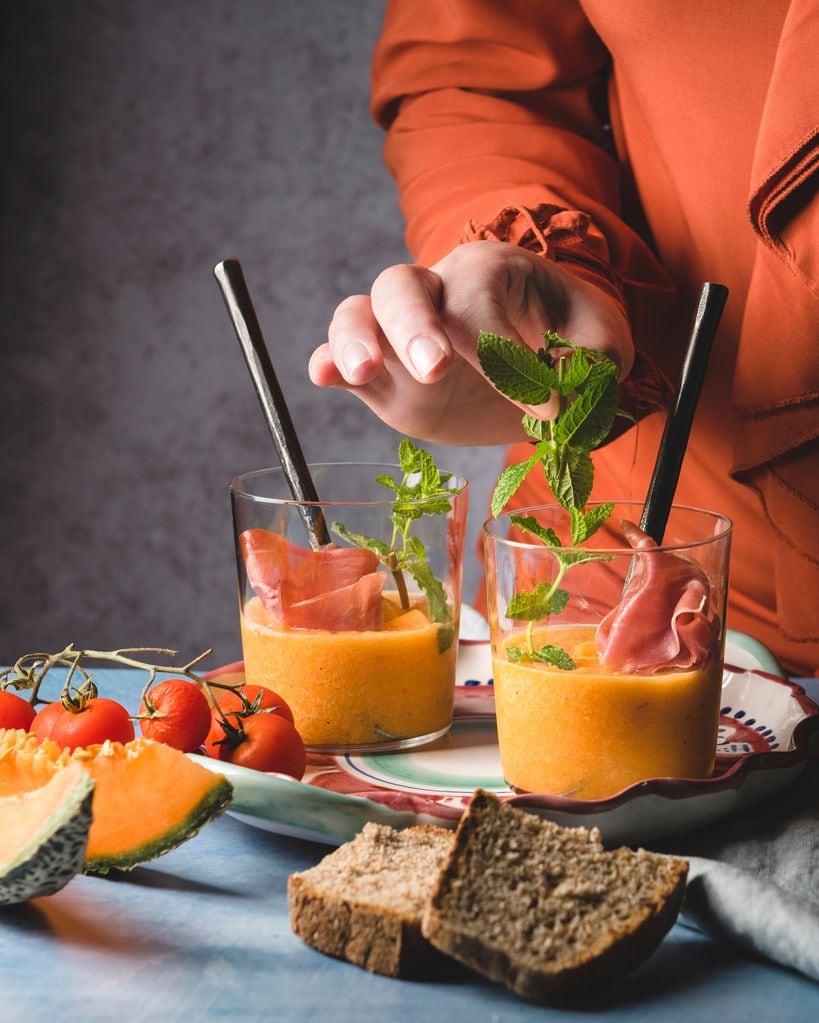 Decorando un gazpacho de melón y jamón con unas hojas de menta