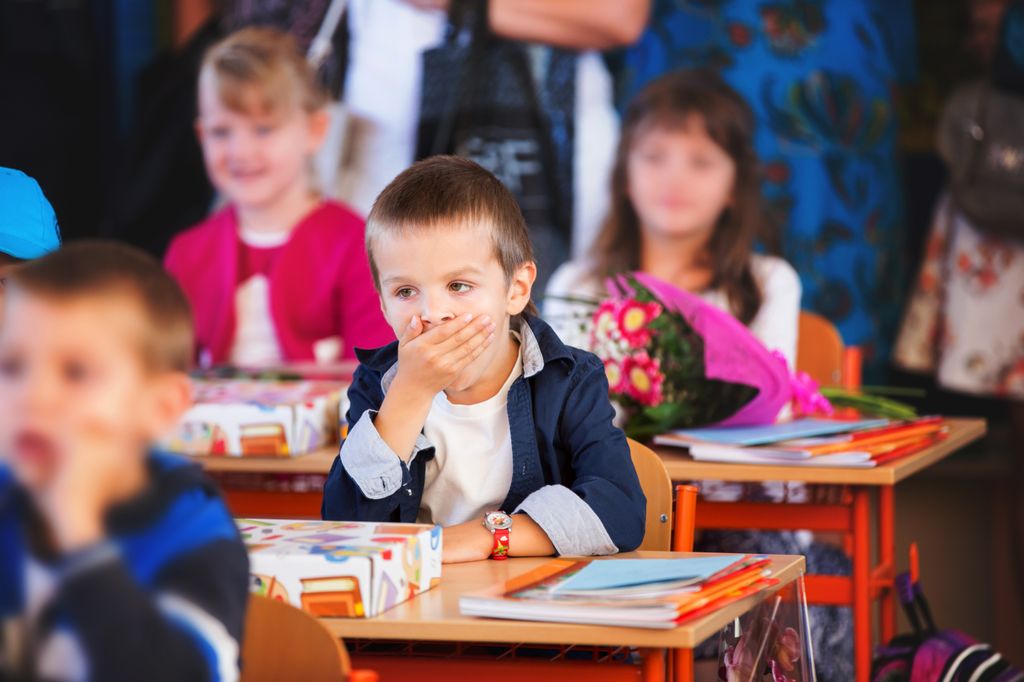 Niño sentado en su pupitre bostezando en clase