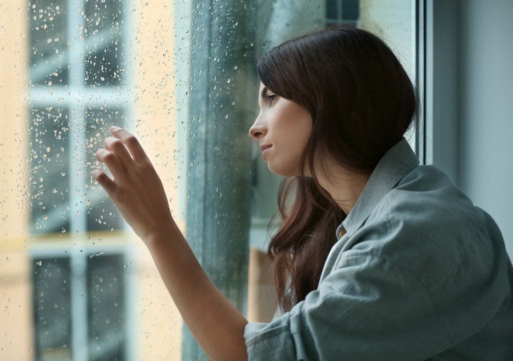 mujer deprimida mirando por la ventana