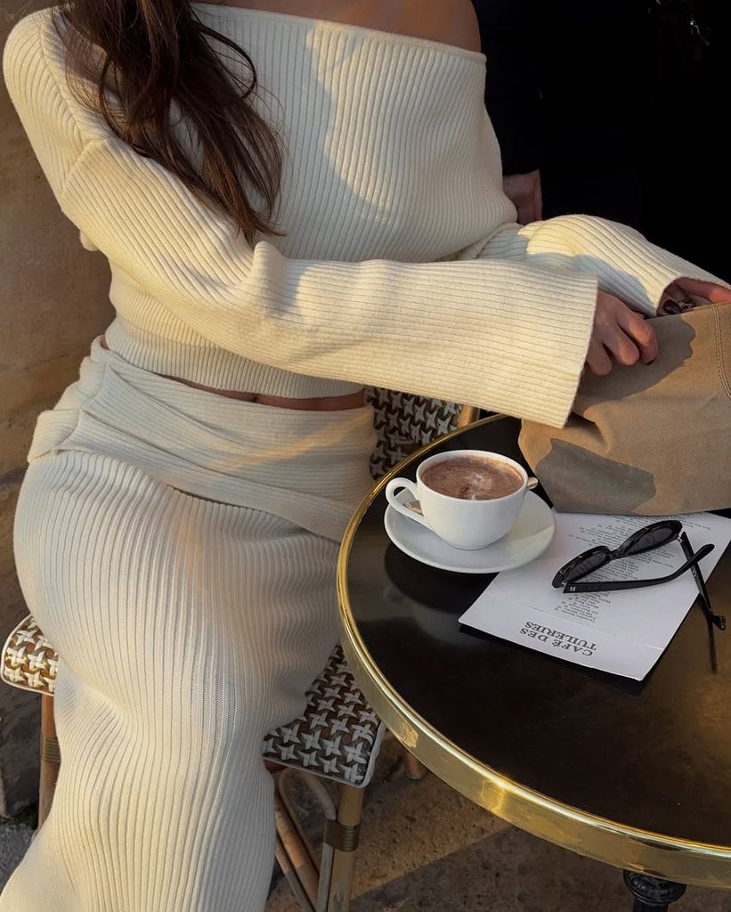 Mujer conjunto blanco sentada en mesa con café