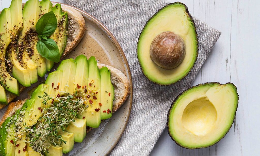 tostadas con rodajas de aguacate hojas de albahaca y condimentos 