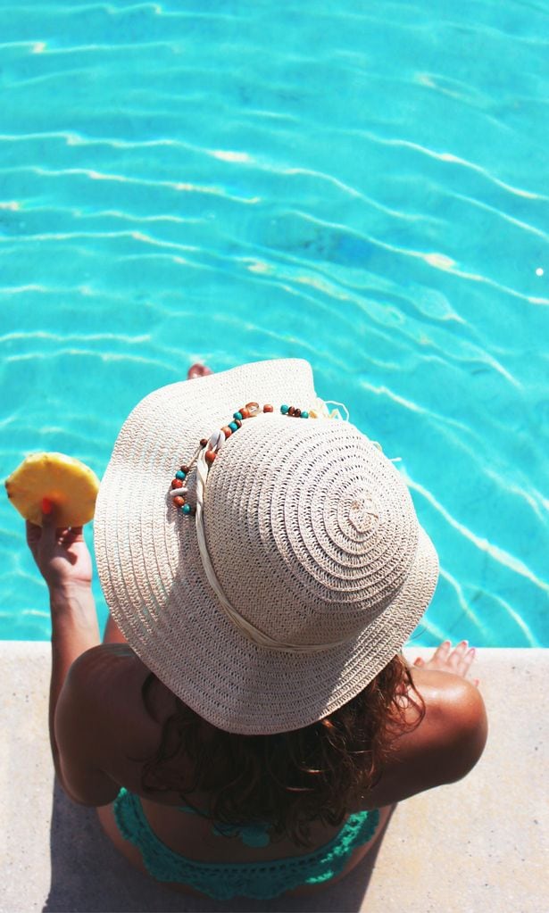 Chica con sombrero de paja en la piscina