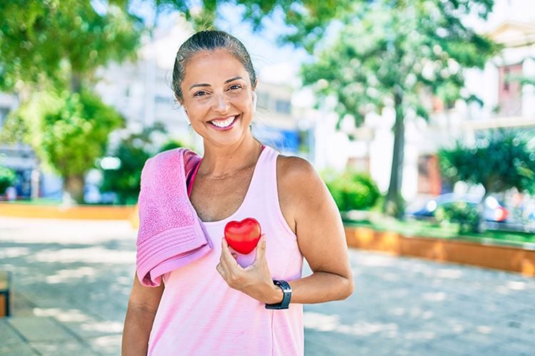 Deportista de mediana edad pidiendo atención médica y sosteniendo el corazón en el parque