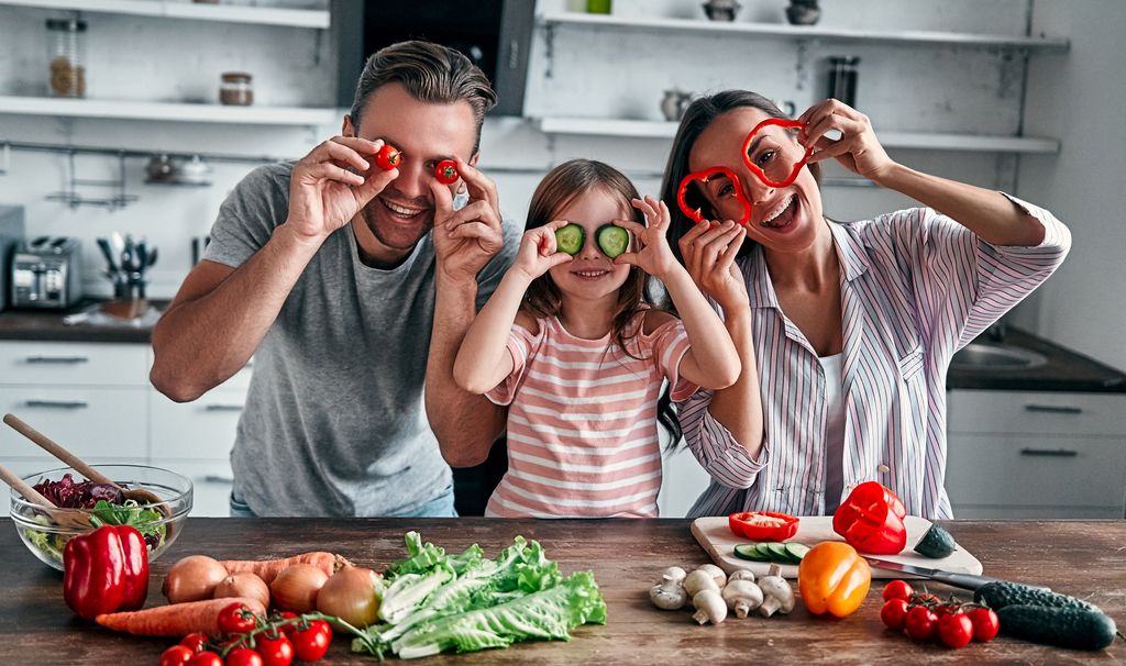 Familia en la cocina felices con verduras