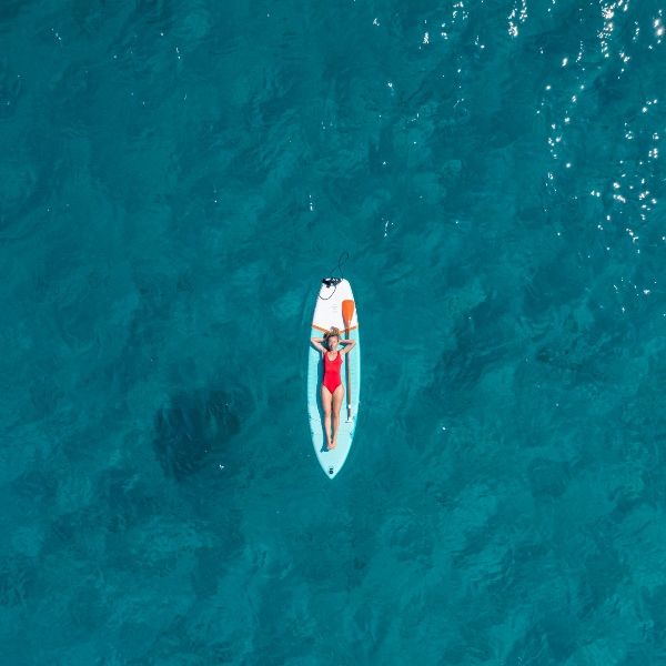 Persona acostada sobre una tabla de paddle surf