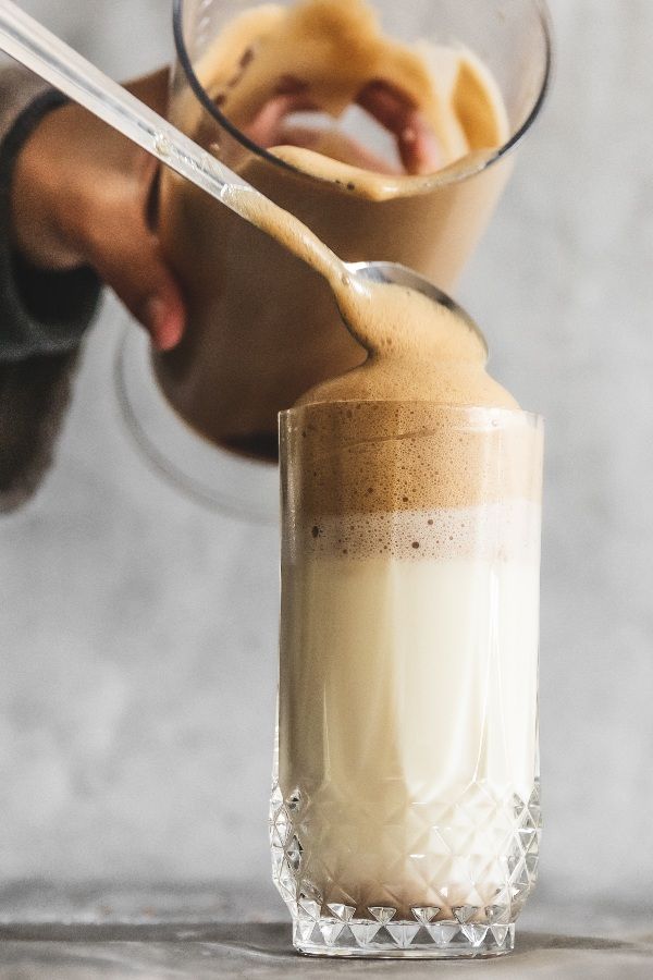 Persona usando un espumador de leche en la preparación de un café