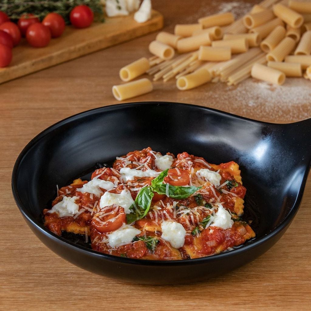 Ravioloni de pasta fresca rellena de requesón y espinacas se acompaña de una deliciosa salsa de tomate, mozzarella de búfala, tomates cherry y rúcula.