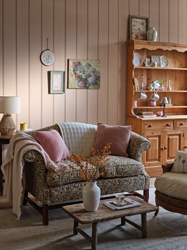 Salón de estilo vintage con sofá con estampado floral y estantería de madera. 