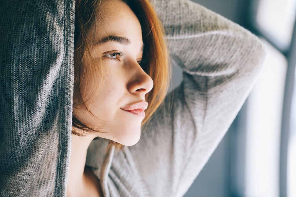 mujer seria mirando por la ventana