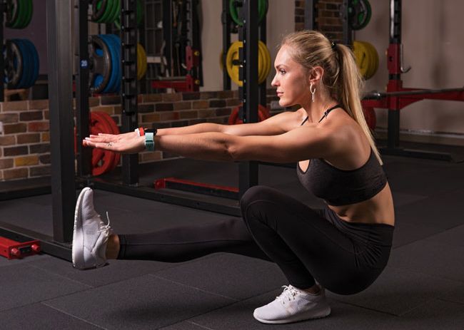 Mujer haciendo sentadilla pistol en el gimnasio