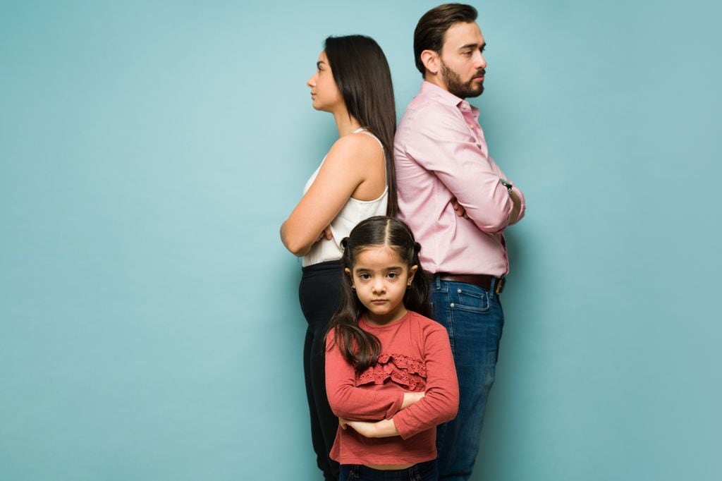 Padres divorciados con hija en medio en actitud seria