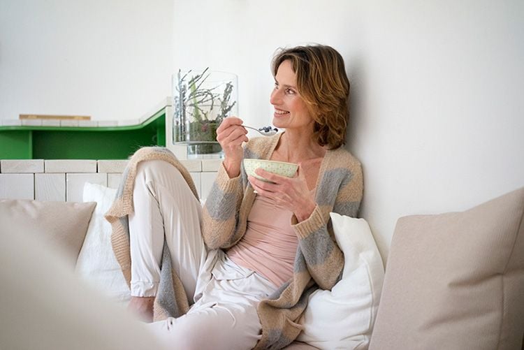 Mujer sentada relajada comiendo comida saludable