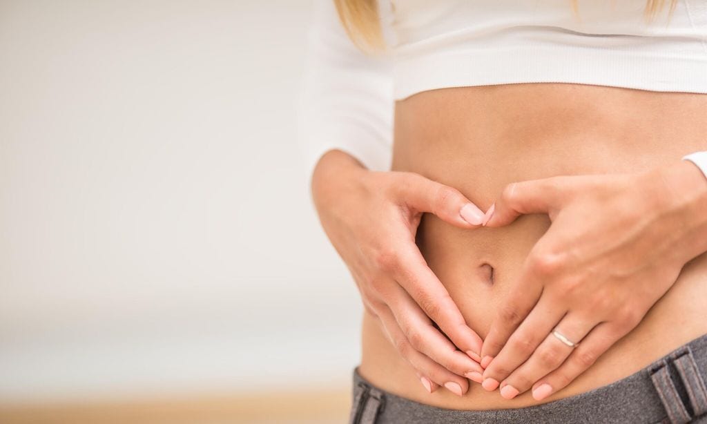 mujer con manos en la tripa en forma de coraz n