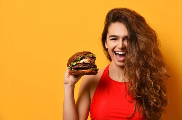 mujer con el pelo largo comiendo una hamburguesa