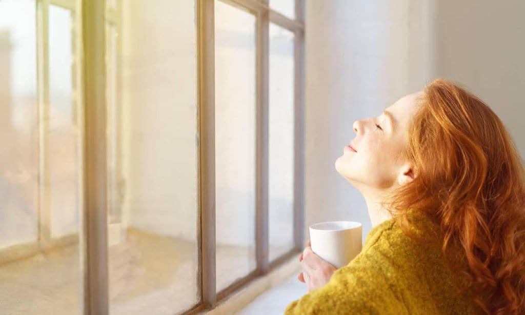 mujer feliz mirando por la ventana