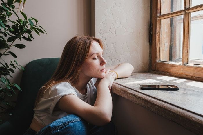 mujer pensativa mirando por una ventana