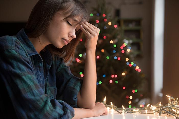 mujer pensativa junto al árbol de Navidad