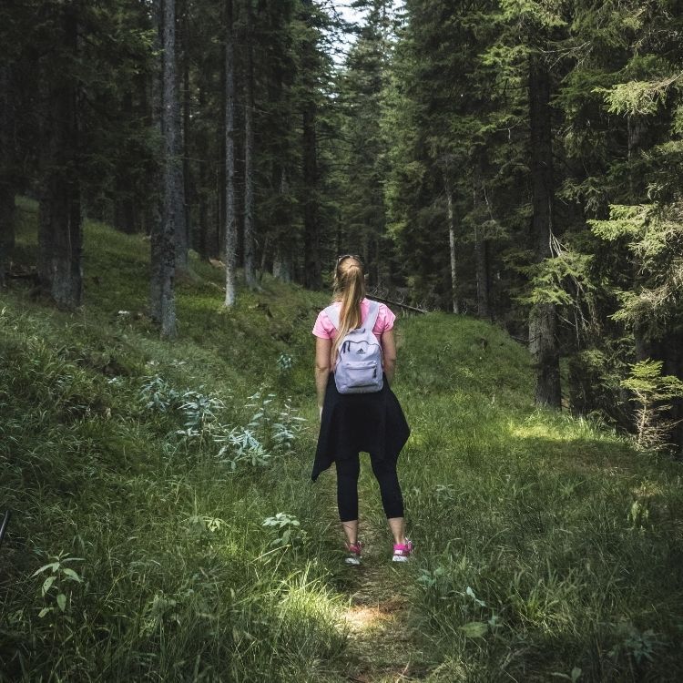 Mujer caminando de espaldas en un bosque