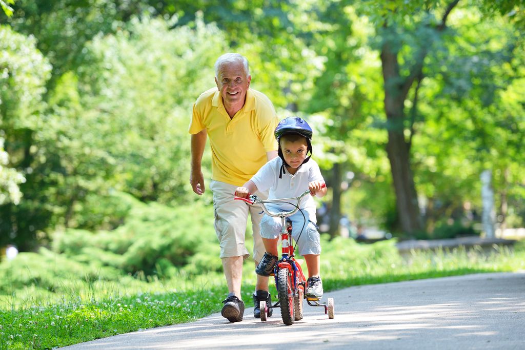 Abuelo ayudando a su nieto con la bicicleta
